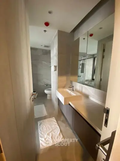 Modern bathroom with sleek fixtures and large mirror in a stylish apartment.