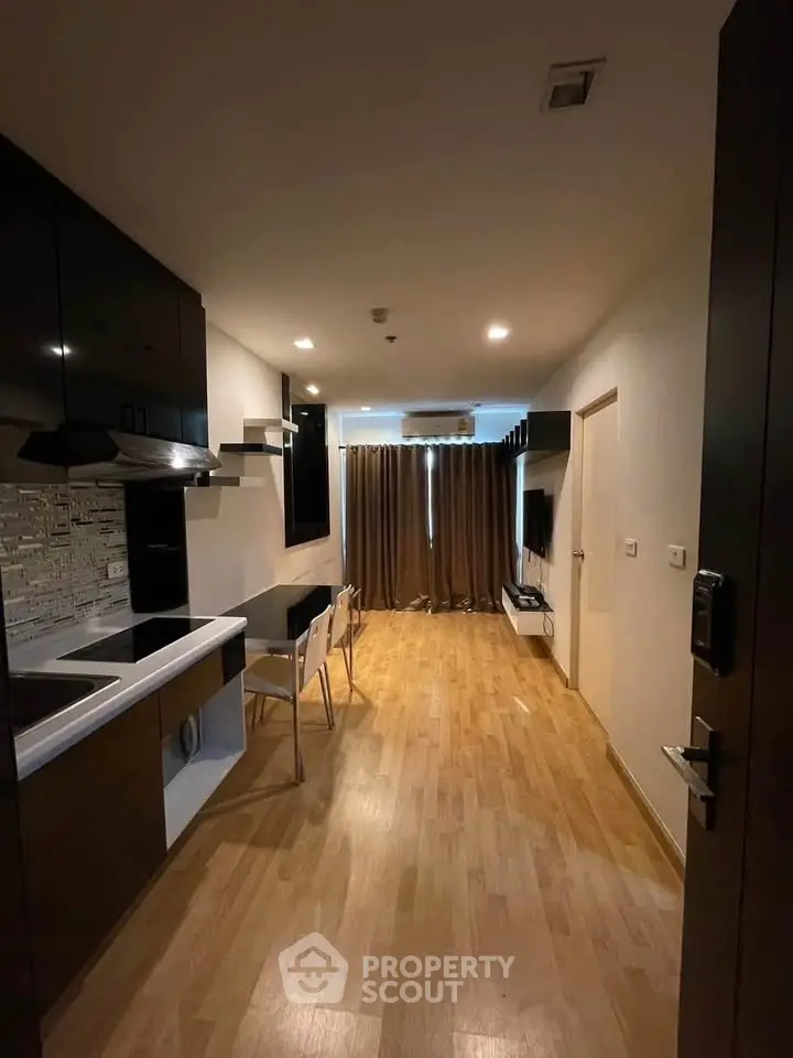 Modern apartment interior with sleek kitchen and cozy living area, featuring wooden flooring and stylish furnishings.