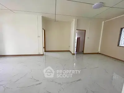 Spacious empty room with glossy marble flooring and neutral walls.