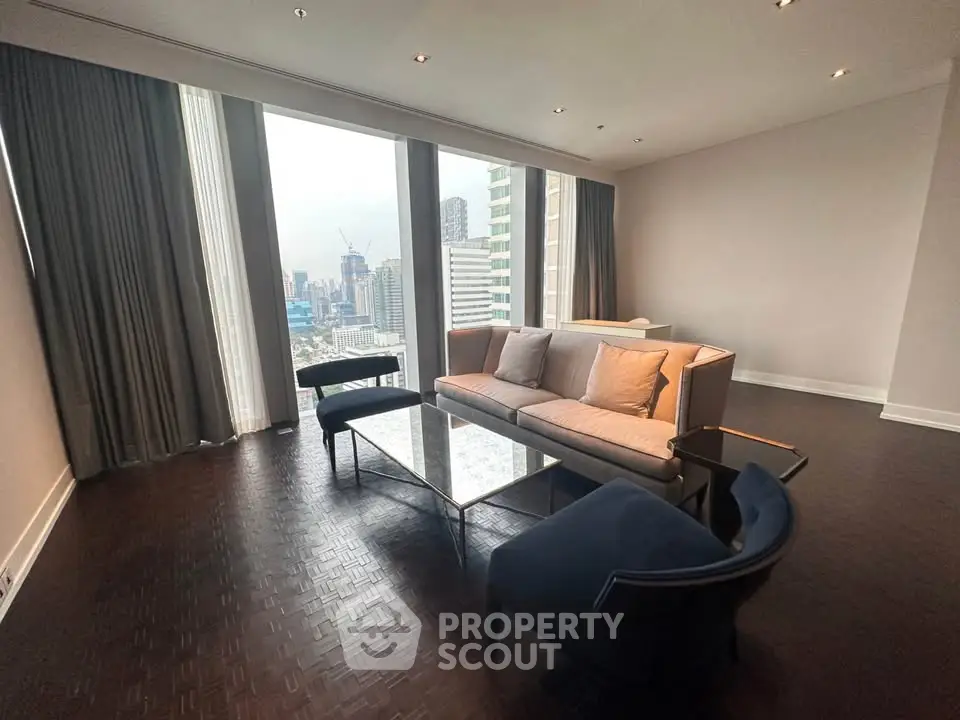 Spacious modern living room with city view, featuring elegant furniture and floor-to-ceiling windows.
