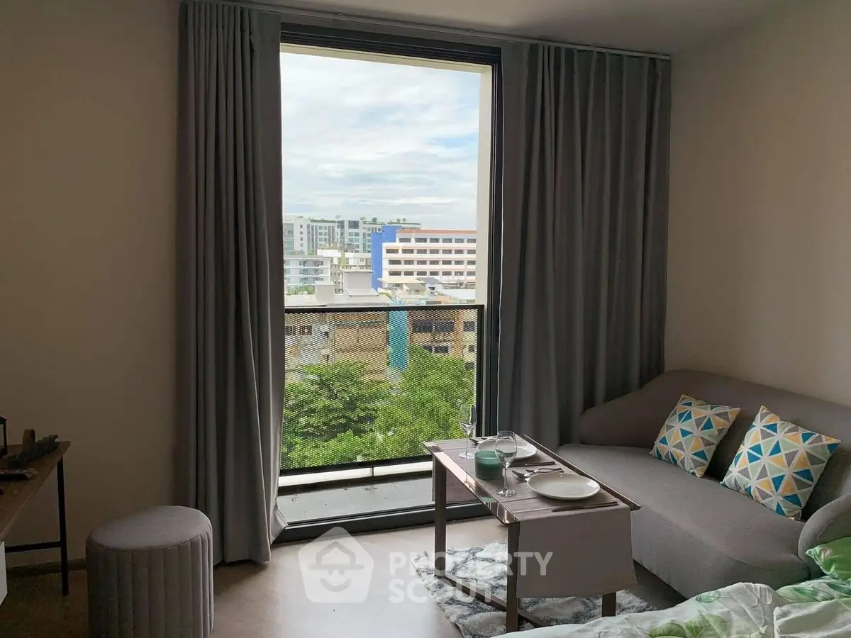 Cozy living room with large window and city view, perfect for relaxation.