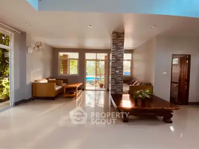 Spacious living room with modern decor and large windows overlooking a garden.