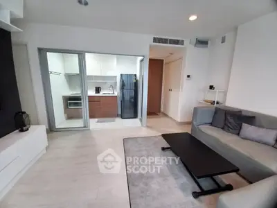 Modern living room with open kitchen, sleek furniture, and stylish decor in a contemporary apartment.