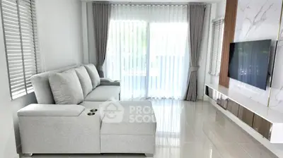 Modern living room with sleek gray sectional sofa and wall-mounted TV, featuring floor-to-ceiling windows and elegant drapes.