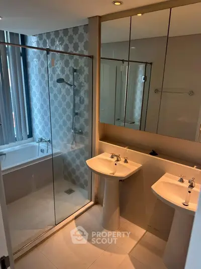 Luxurious bathroom with dual sinks and glass-enclosed shower in modern apartment.