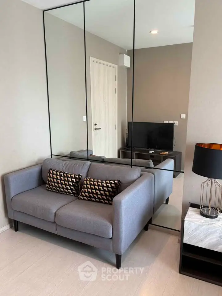 Modern living room with stylish gray sofa and mirrored wall decor