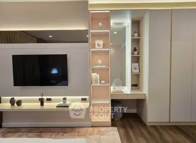 Modern bedroom with built-in TV unit and stylish shelving, featuring elegant decor and warm lighting.
