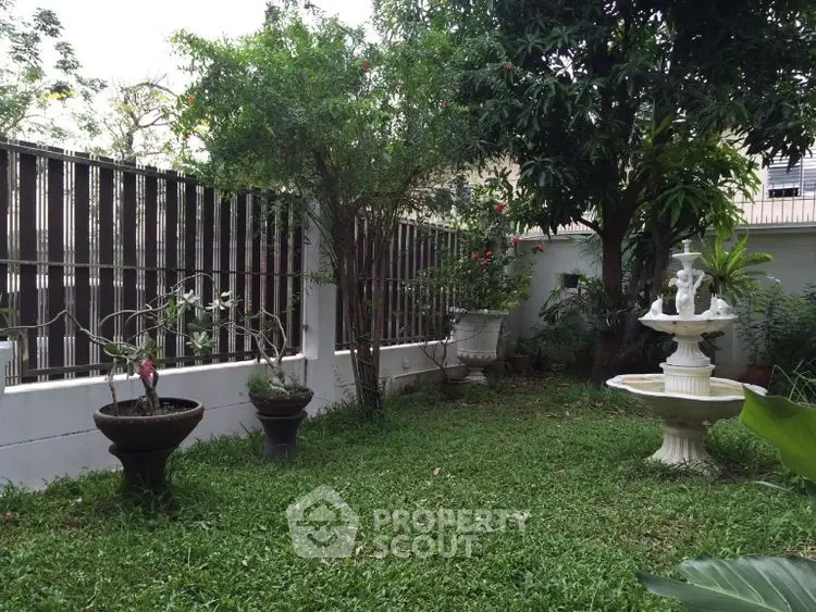 Charming garden with lush greenery and elegant fountain in a serene backyard setting.