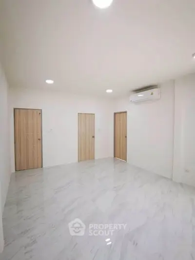 Spacious minimalist room with marble flooring and air conditioning, ideal for modern living.