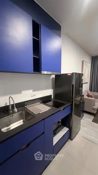 Modern kitchen with sleek blue cabinets and stainless steel appliances in a stylish apartment.