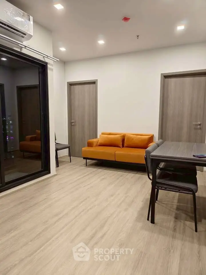Modern living room with orange sofa and dining area in stylish apartment
