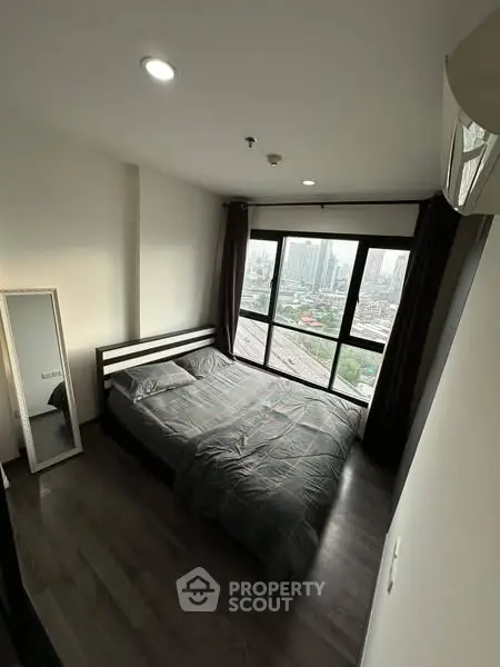 Modern bedroom with city view and large window in high-rise apartment