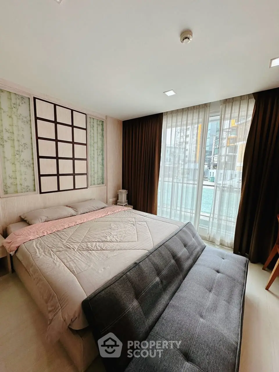 Spacious bedroom with modern decor and large window offering natural light