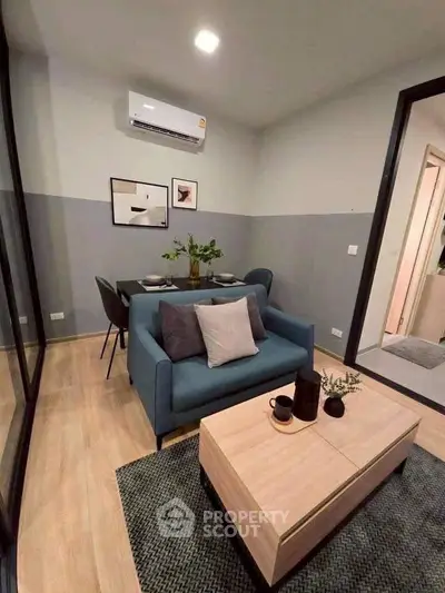 Modern living room with stylish decor and dining area, featuring a cozy blue sofa and elegant wooden table.
