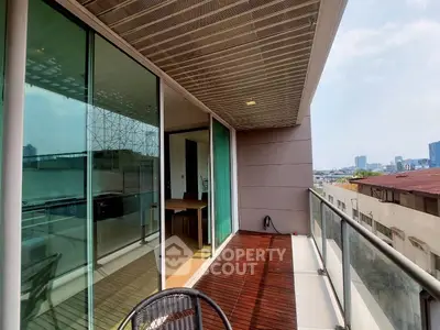 Spacious balcony with city view and modern glass railing, perfect for relaxation.