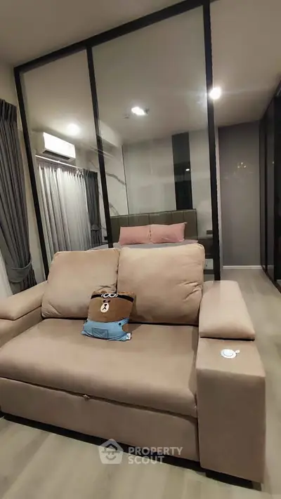 Modern living room with stylish beige sofa and glass partition in contemporary apartment.