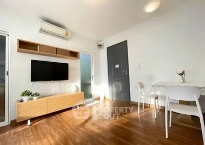 Bright modern living room with wooden flooring, wall-mounted TV, and dining area.