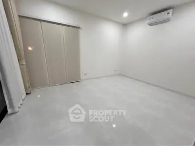 Spacious empty room with sleek tiled flooring and air conditioning, perfect for customization.