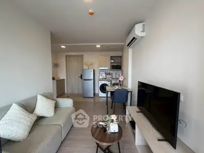 Modern living room with open kitchen, featuring sleek furniture and appliances in a cozy apartment setting.