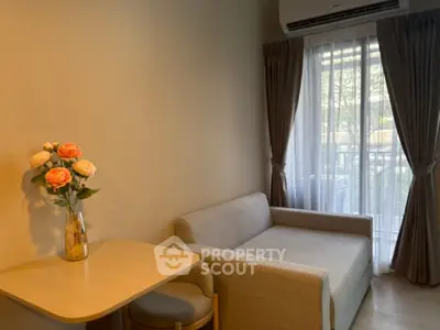 Cozy living room with sofa and natural light from large window, perfect for relaxation.