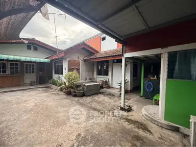 Charming rustic courtyard with potted plants and covered patio in a cozy residential setting.