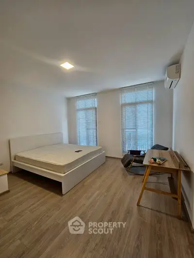 Spacious bedroom with modern decor and natural light, featuring a comfortable bed and stylish desk.