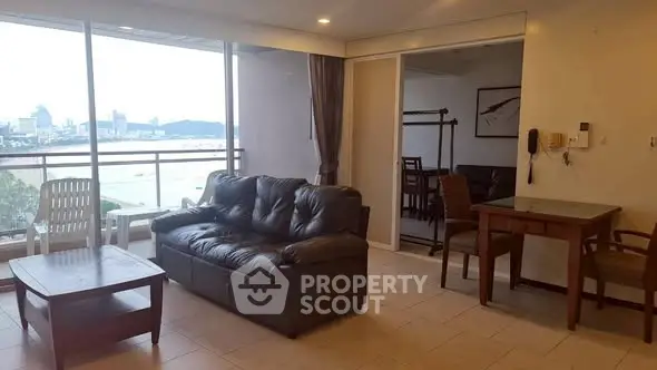 Spacious living room with large windows offering stunning city and river views, perfect for relaxation.
