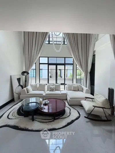 Luxurious living room with high ceilings, elegant decor, and large windows offering abundant natural light.