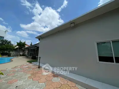 Modern building exterior with pool and patio under a clear blue sky.