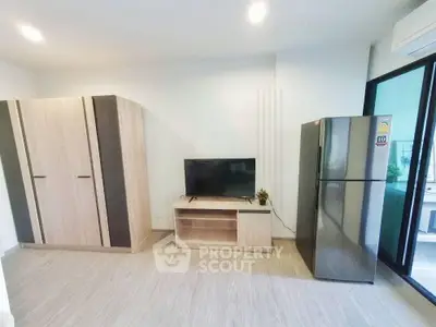Modern living room with sleek TV stand, wardrobe, and stainless steel fridge in a bright apartment.