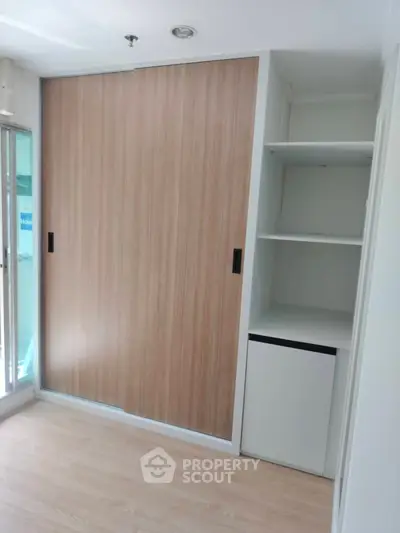 Modern storage space with sliding wooden doors and open shelves in a bright room.