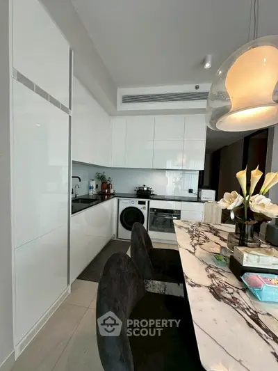 Modern kitchen with sleek white cabinets, marble countertop, and built-in appliances.
