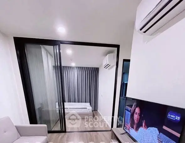 Modern apartment interior with sliding glass doors and air conditioning, featuring a cozy living area and bedroom.