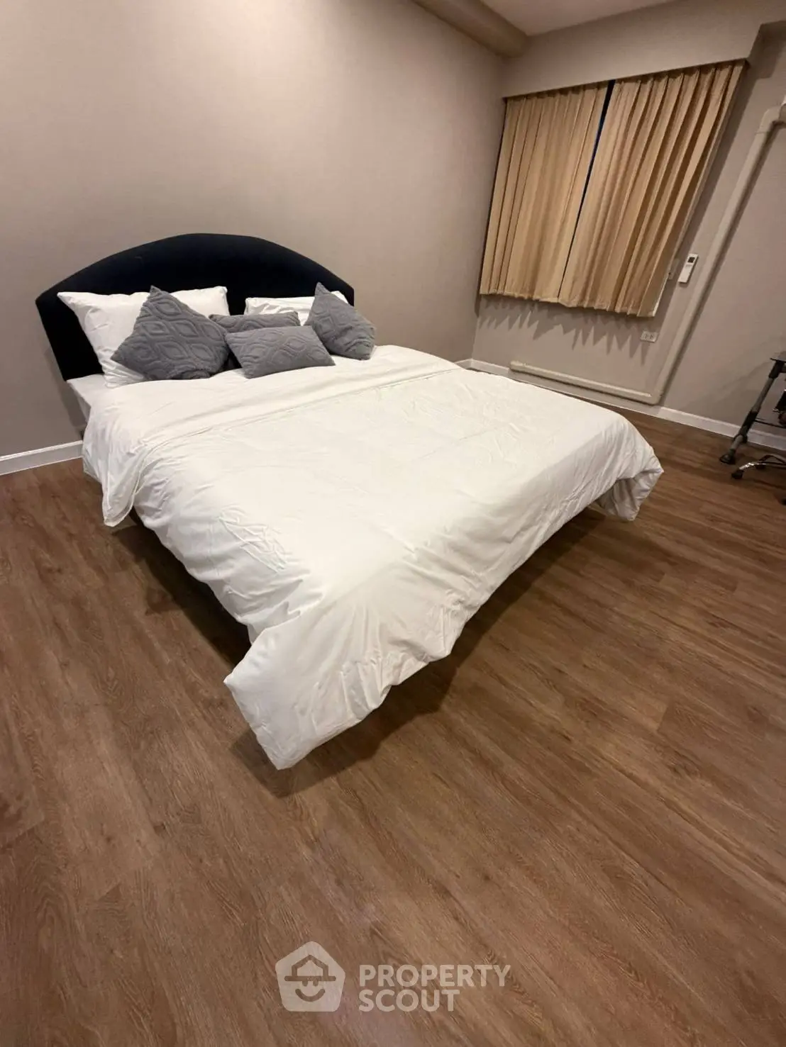 Spacious bedroom with elegant wooden flooring and cozy bed setup
