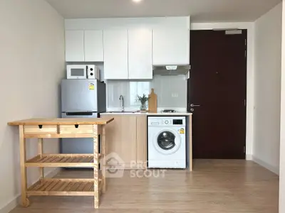Modern compact kitchen with washing machine and wooden cart in cozy apartment.