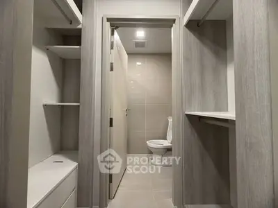 Spacious walk-in closet leading to a modern bathroom with sleek design.