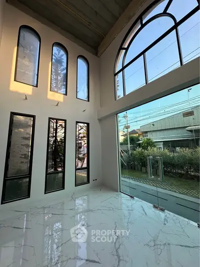 Stunning modern living room with high ceilings and large arched windows offering abundant natural light.