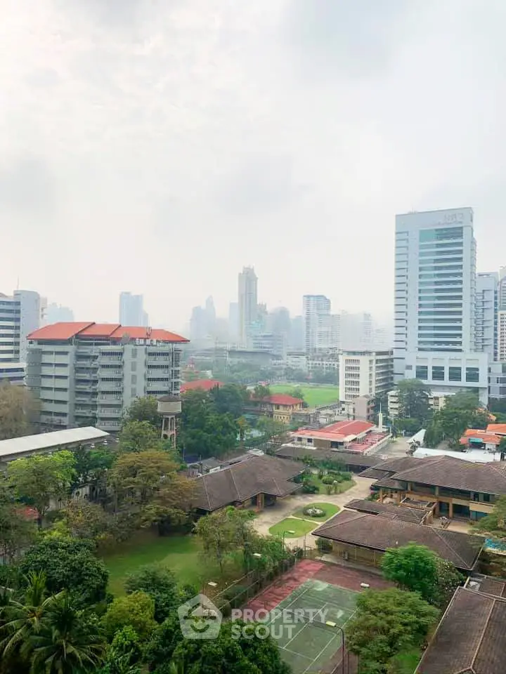 Stunning cityscape view from a high-rise building, showcasing lush greenery and urban skyline.