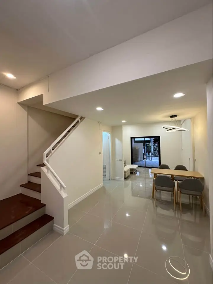 Modern dining area with sleek staircase and elegant lighting in a contemporary home.