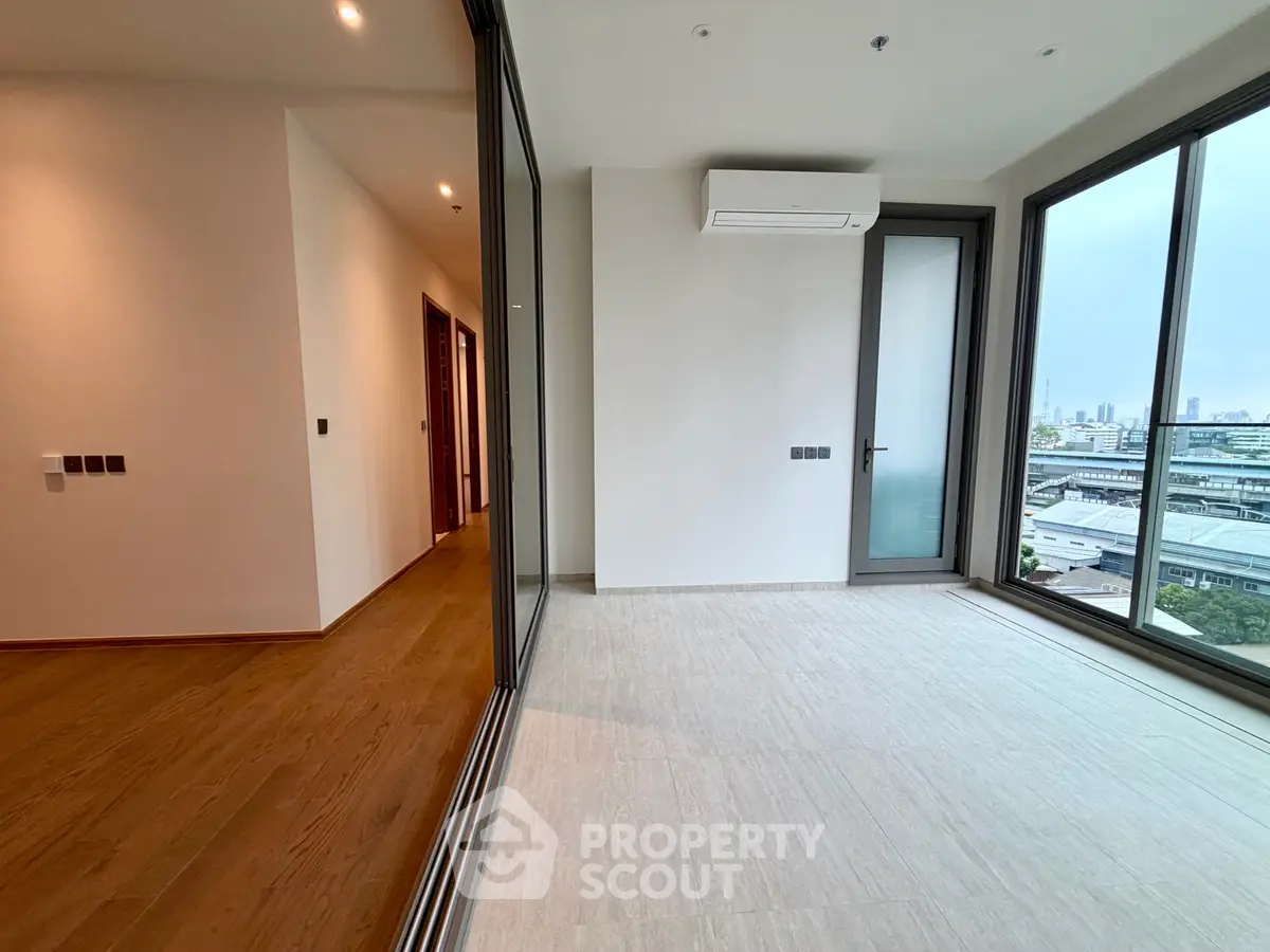 Modern apartment with large windows and city view, featuring sleek flooring and air conditioning.