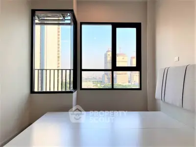 Modern bedroom with large windows offering a stunning city view, perfect for urban living.