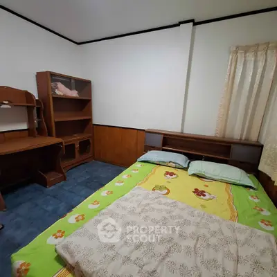 Cozy bedroom with wooden furniture and colorful bedding, perfect for a comfortable living space.