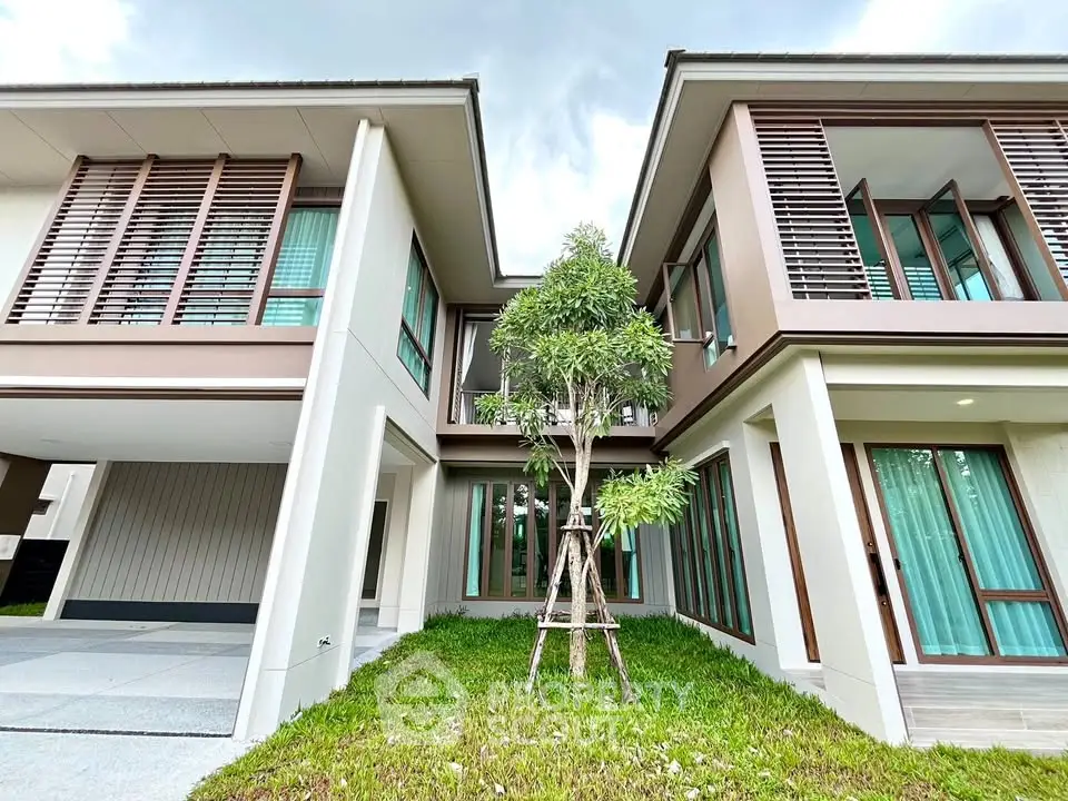 Modern two-story house with large windows and lush green lawn