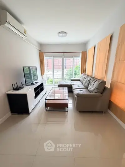 Modern living room with sleek furniture and large windows offering natural light.