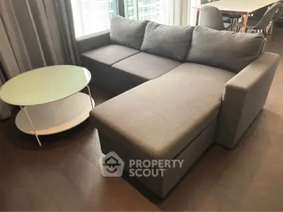 Modern living room with sleek gray sectional sofa and round glass coffee table.