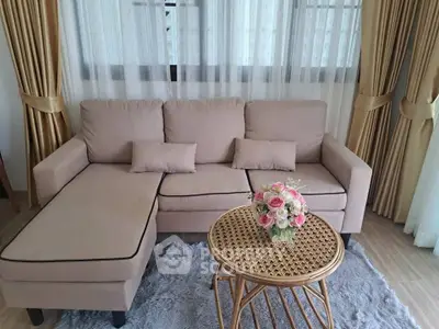 Cozy living room with beige sectional sofa, elegant curtains, and a stylish wicker coffee table.
