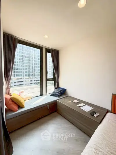 Cozy bedroom with large windows and city view, featuring modern decor and ample natural light.