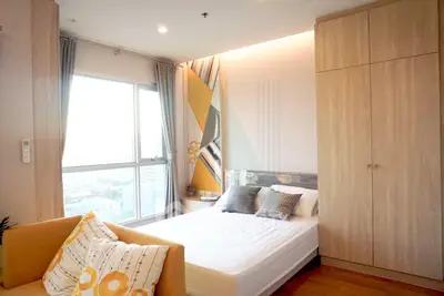 Modern bedroom with large window and stylish decor in a high-rise apartment.