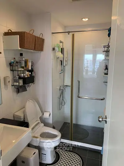 Modern bathroom with glass shower, toilet, and storage baskets, showcasing sleek design and functionality.