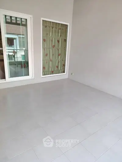 Spacious tiled room with large window and sliding glass door, perfect for versatile use.